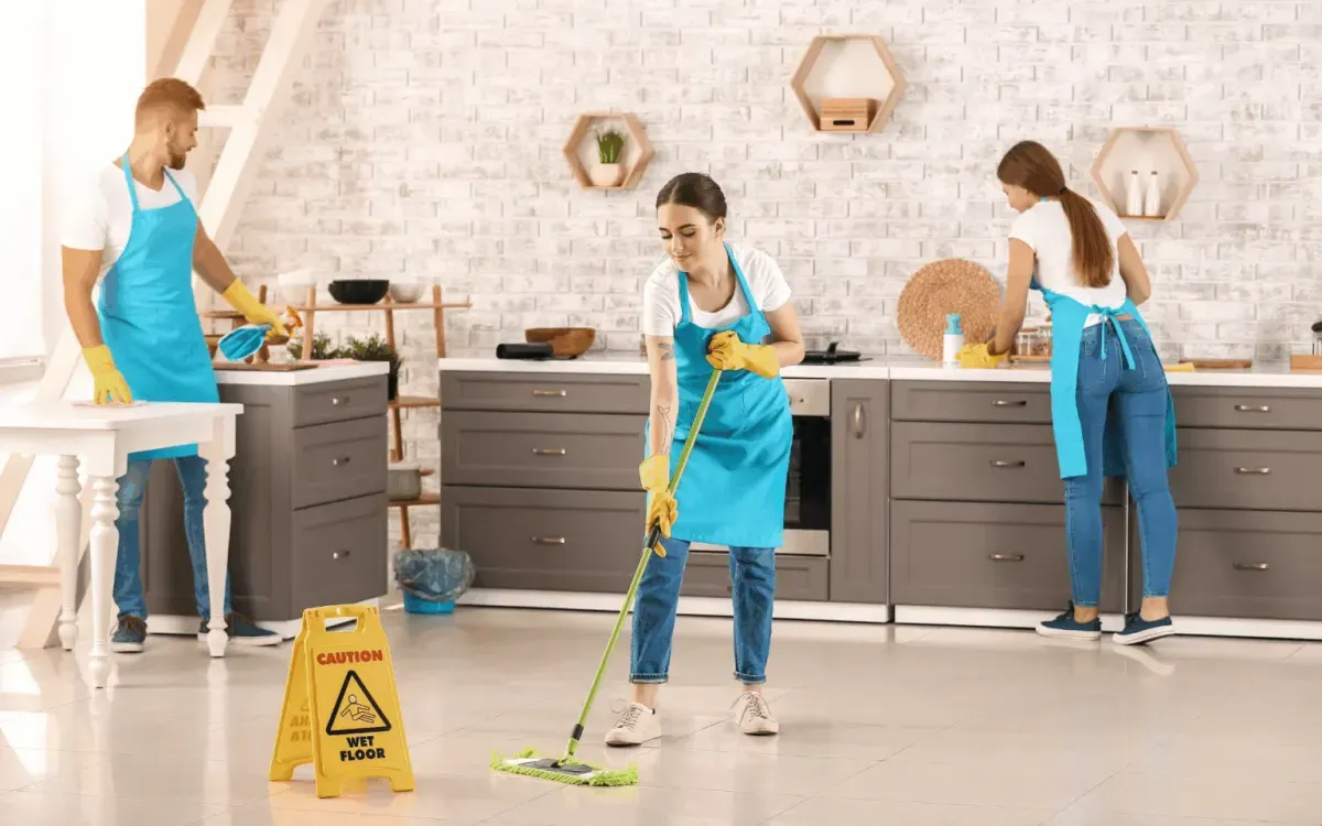 Team cleaning kitchen floor and counters with mop – residential kitchen cleaning services.