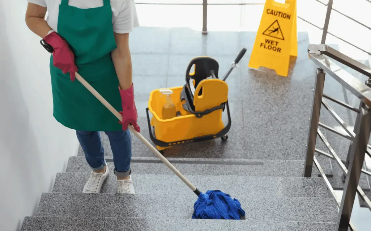 Staircase cleaning service with mop, bucket, and wet floor safety sign.